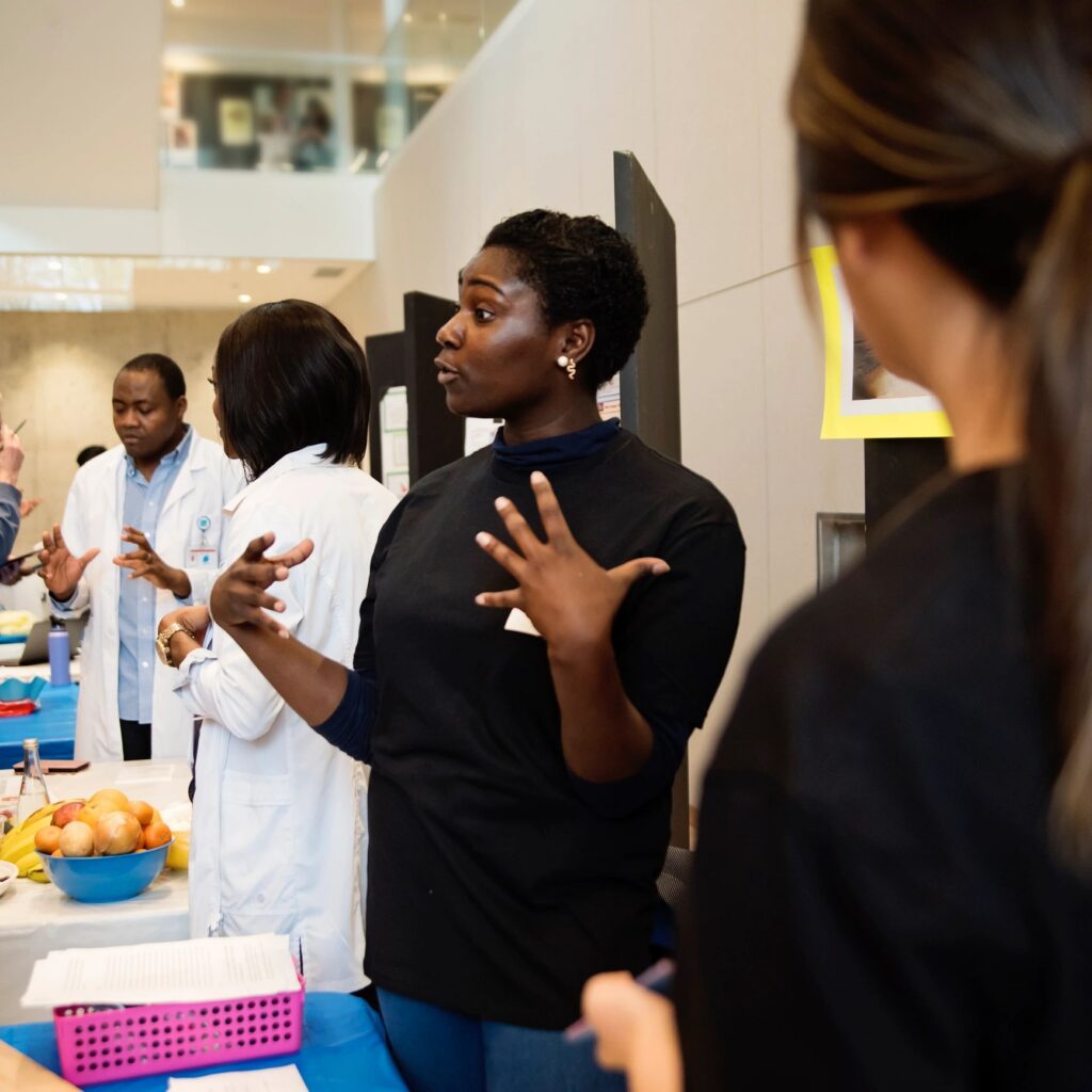 Young adult college student at their kiosk in science fair.